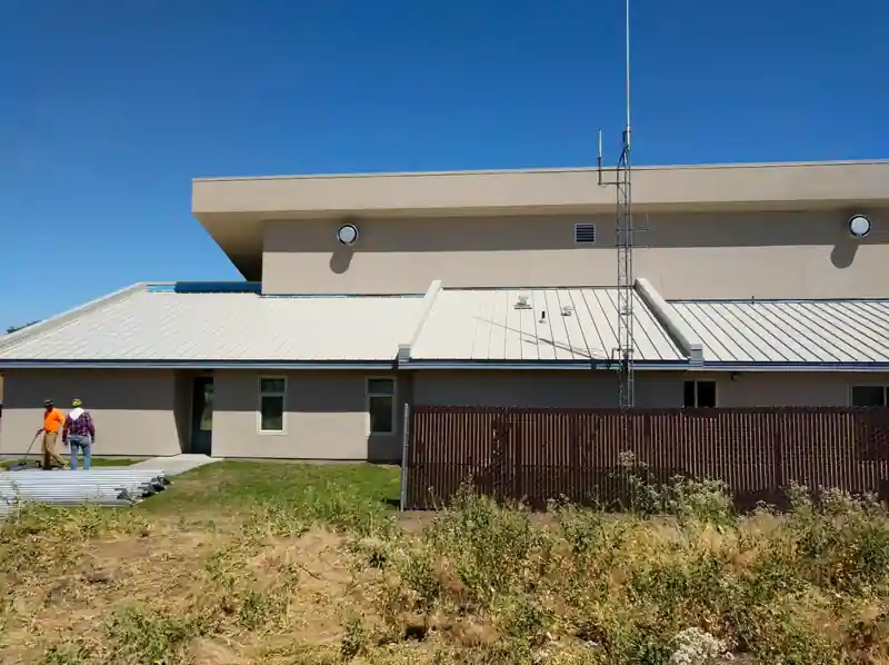 Flat roof public building with a standing-seam lower roof and two crew members walking the roof