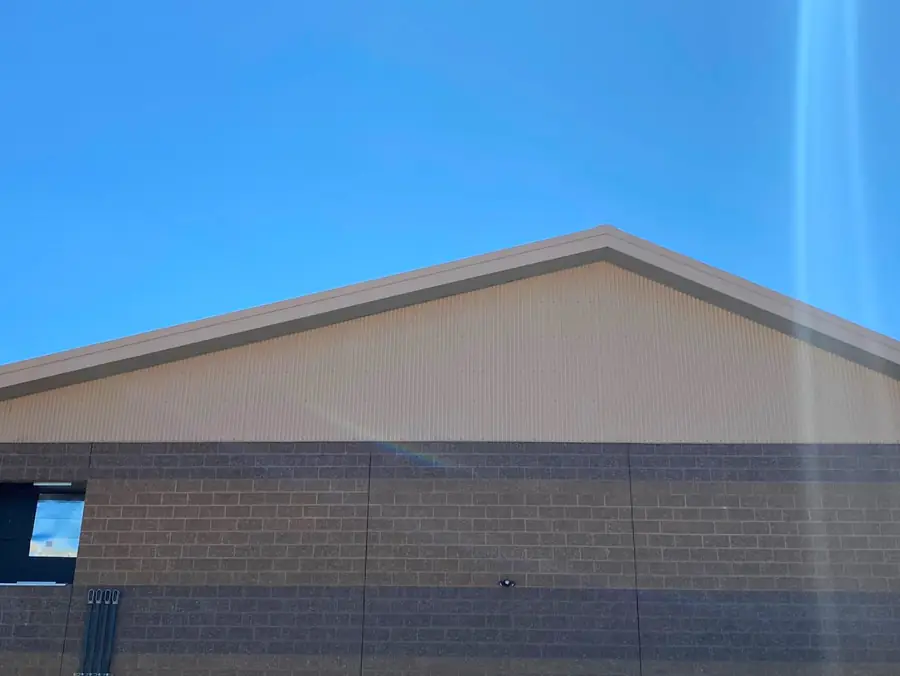 Gable of a tan metal roof over a block wall