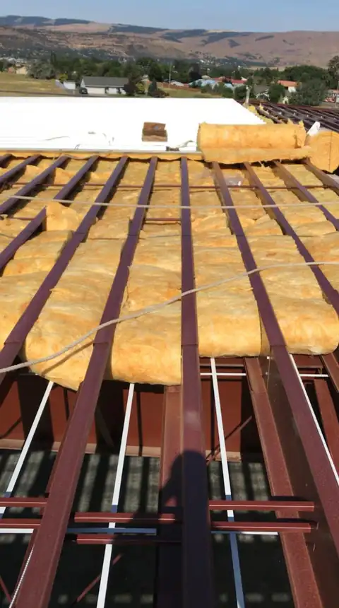 Insulation and purlins mid-install on a metal roof