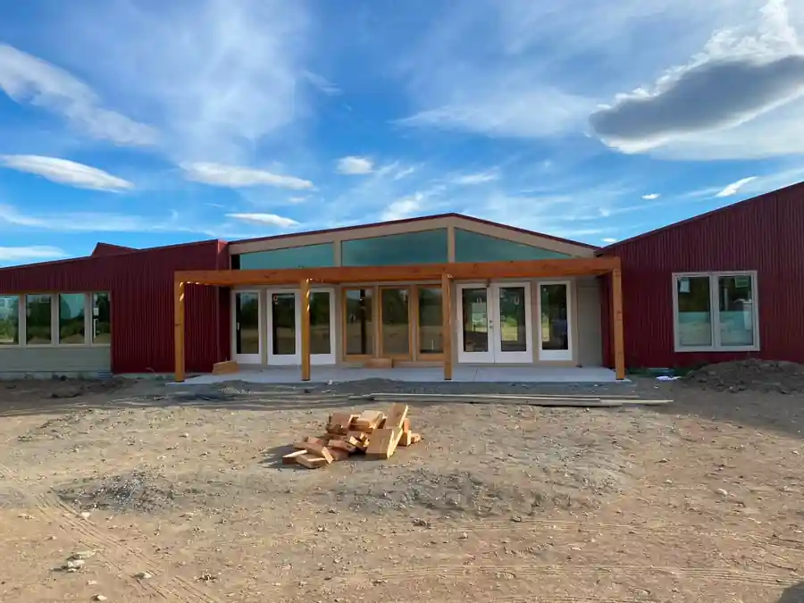 Red corrugated metal building with a timber pergola