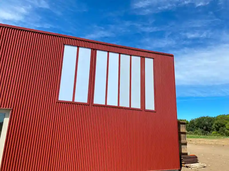 Red corrugated metal wall with a vertical window strip under a blue sky