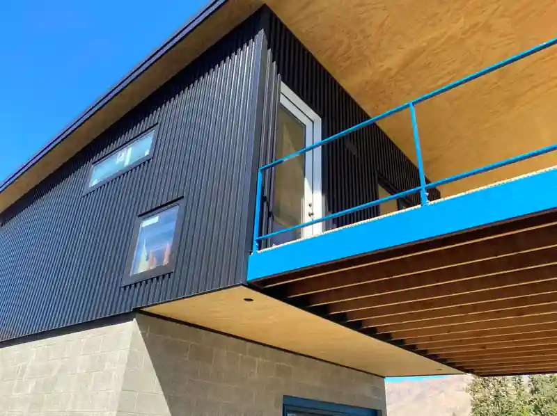 Black metal-walled building with a cantilevered blue deck