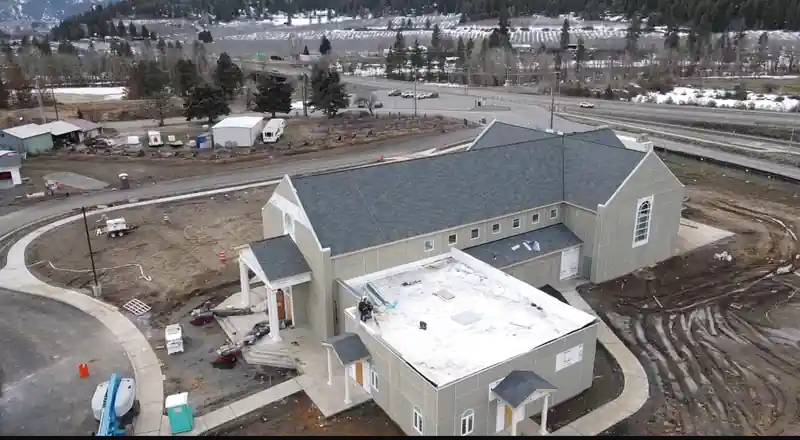 Drone view of a building with a new white flat roof section and new shingles