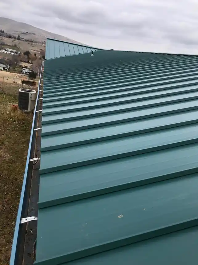 Teal standing-seam roof running along the eave