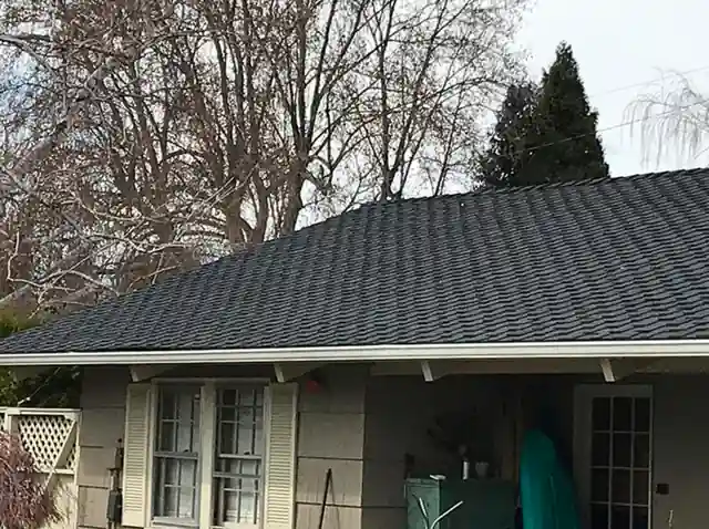 House with a new dark shingle roof seen from the yard